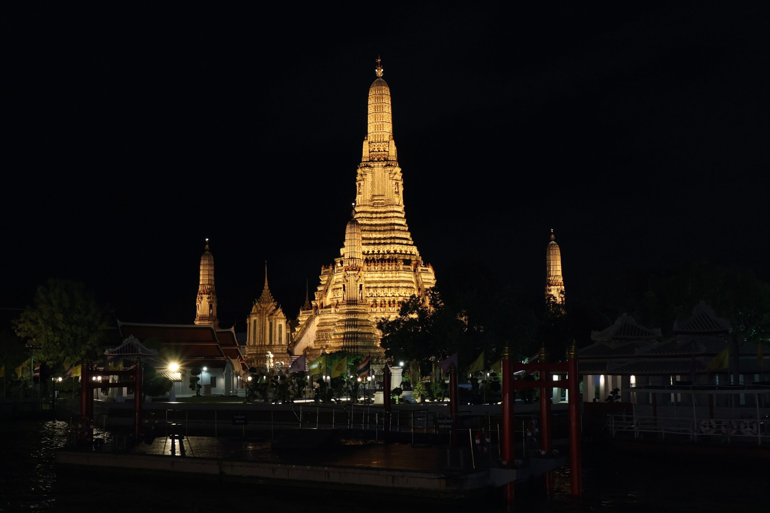 Wat Arun iluminado visto desde el río Chao Phraya en Bangkok